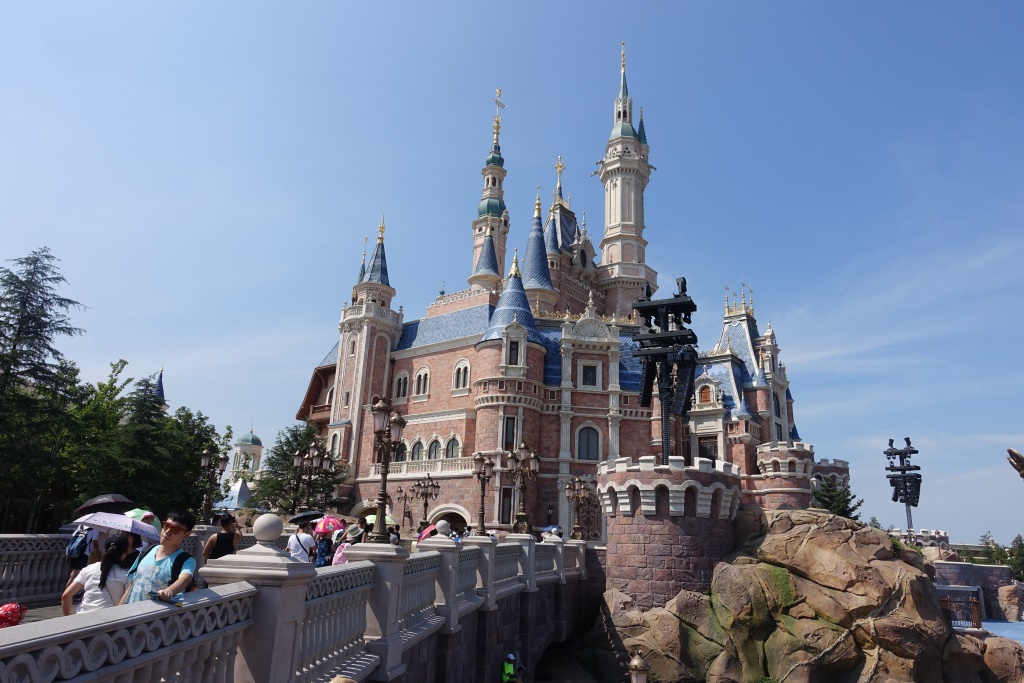 The Enchanted Storybook Castle at Shanghai Disneyland, with guests walking on a nearby bridge.