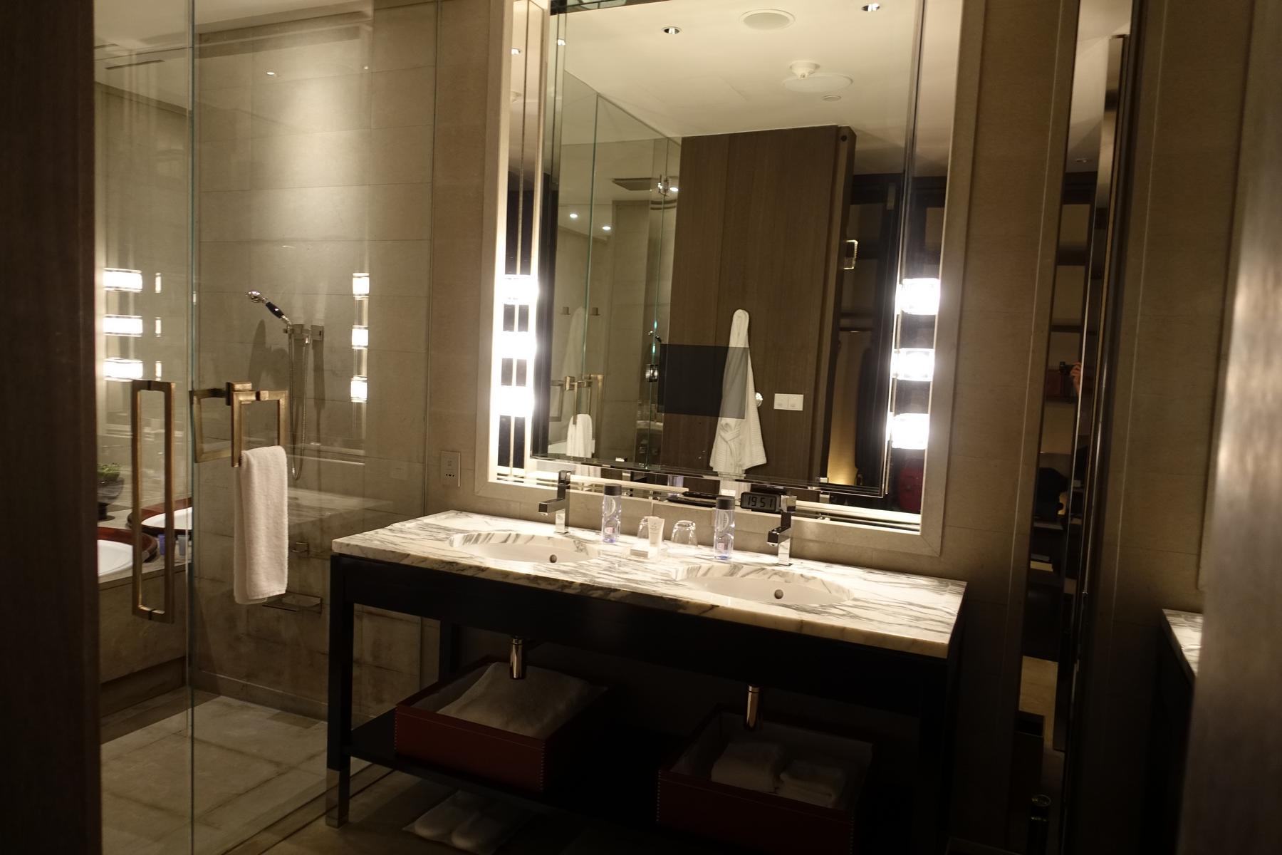 Luxurious hotel bathroom with a double marble vanity and glass-enclosed shower.