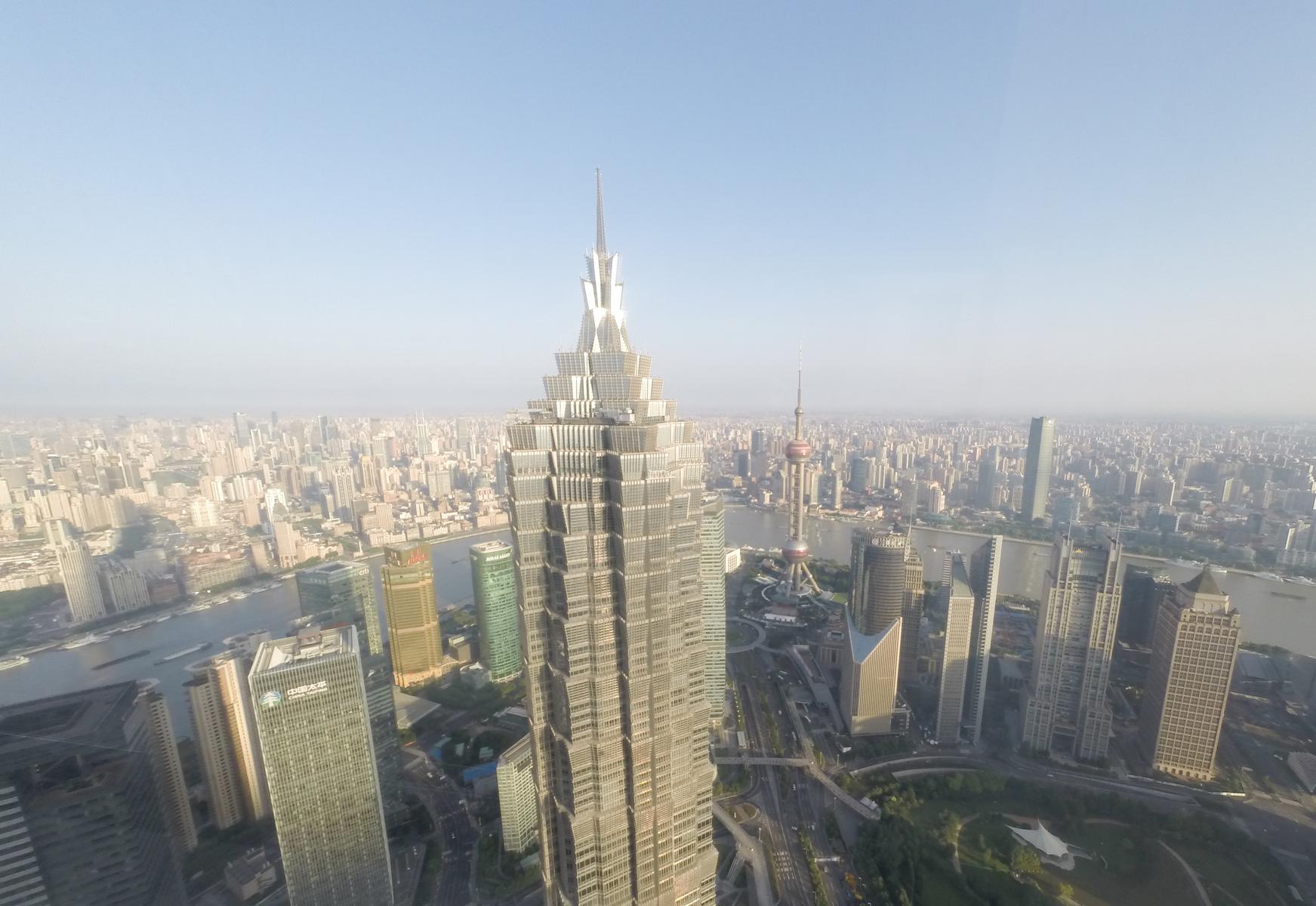 An aerial view of Shanghai's sprawling cityscape, featuring the Jin Mao Tower and Oriental Pearl TV Tower.