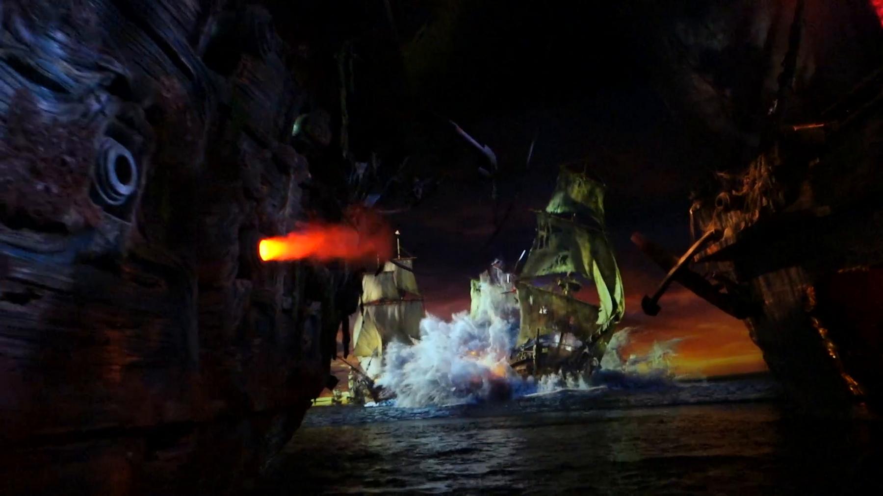A cannon fires from a pirate ship during an immersive sea battle on the Pirates of the Caribbean ride.