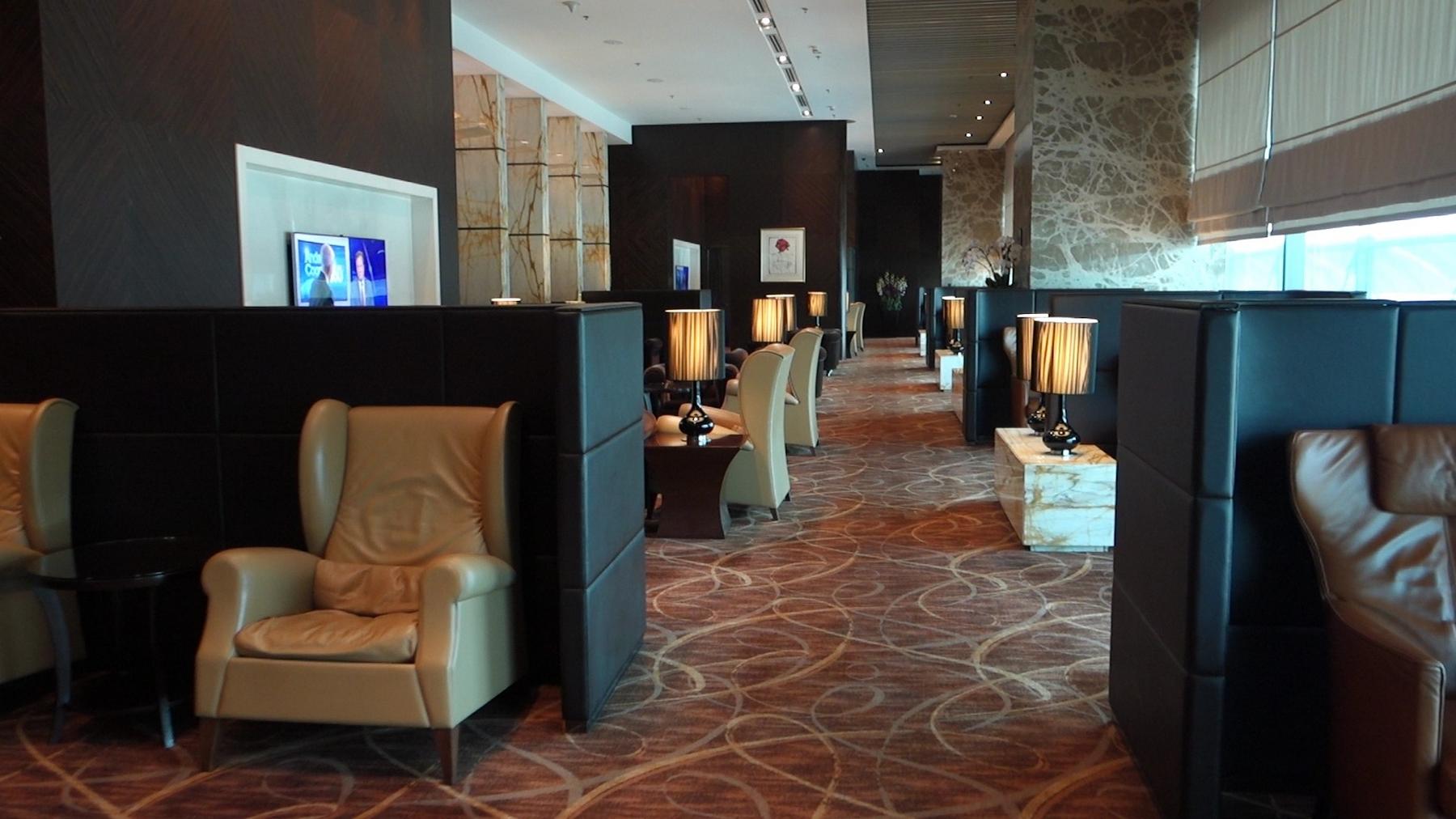A luxurious Singapore Airlines lounge features private seating areas with plush armchairs and elegant lamps.