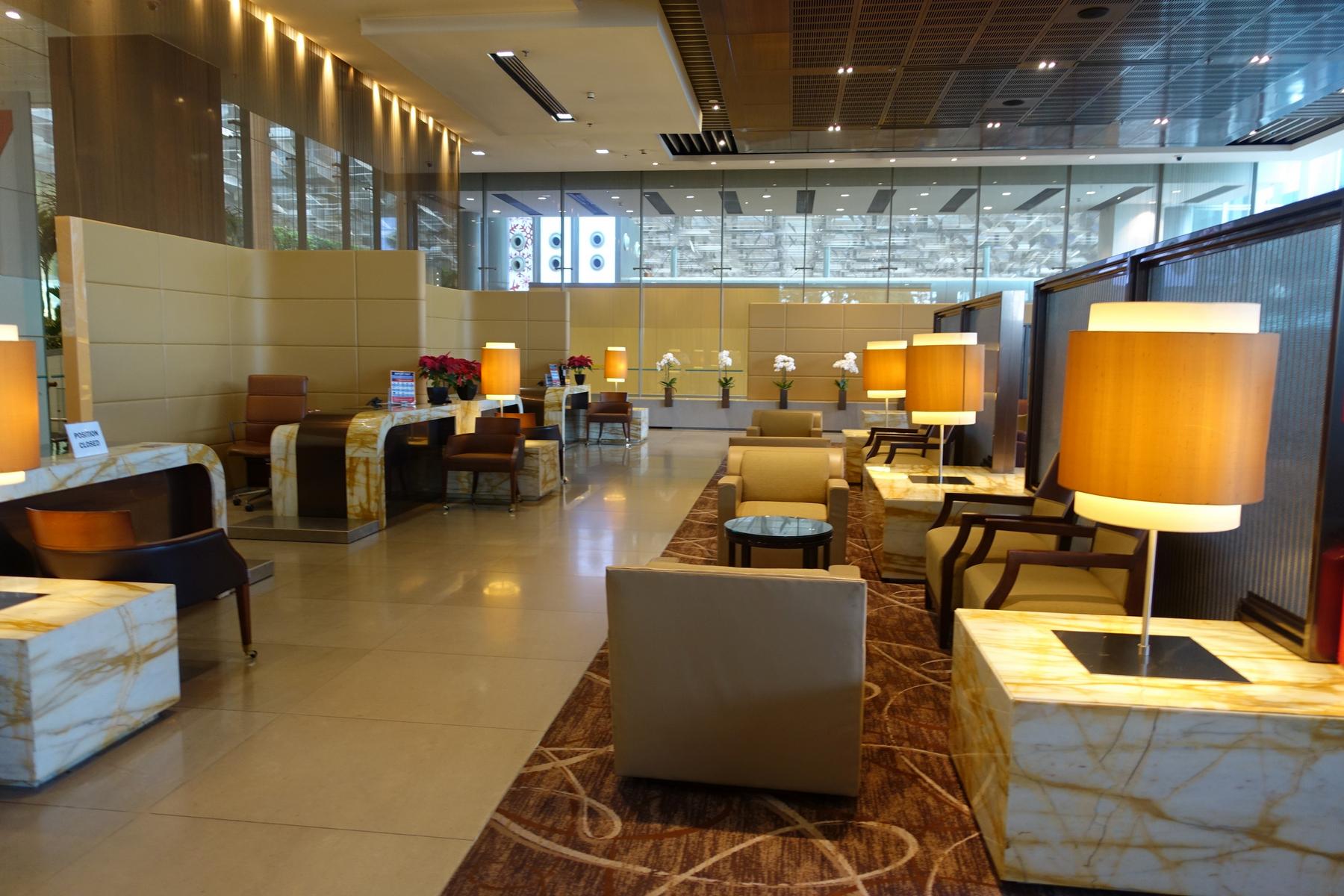 A luxurious airport lounge with comfortable seating, marble desks, and warm lighting.