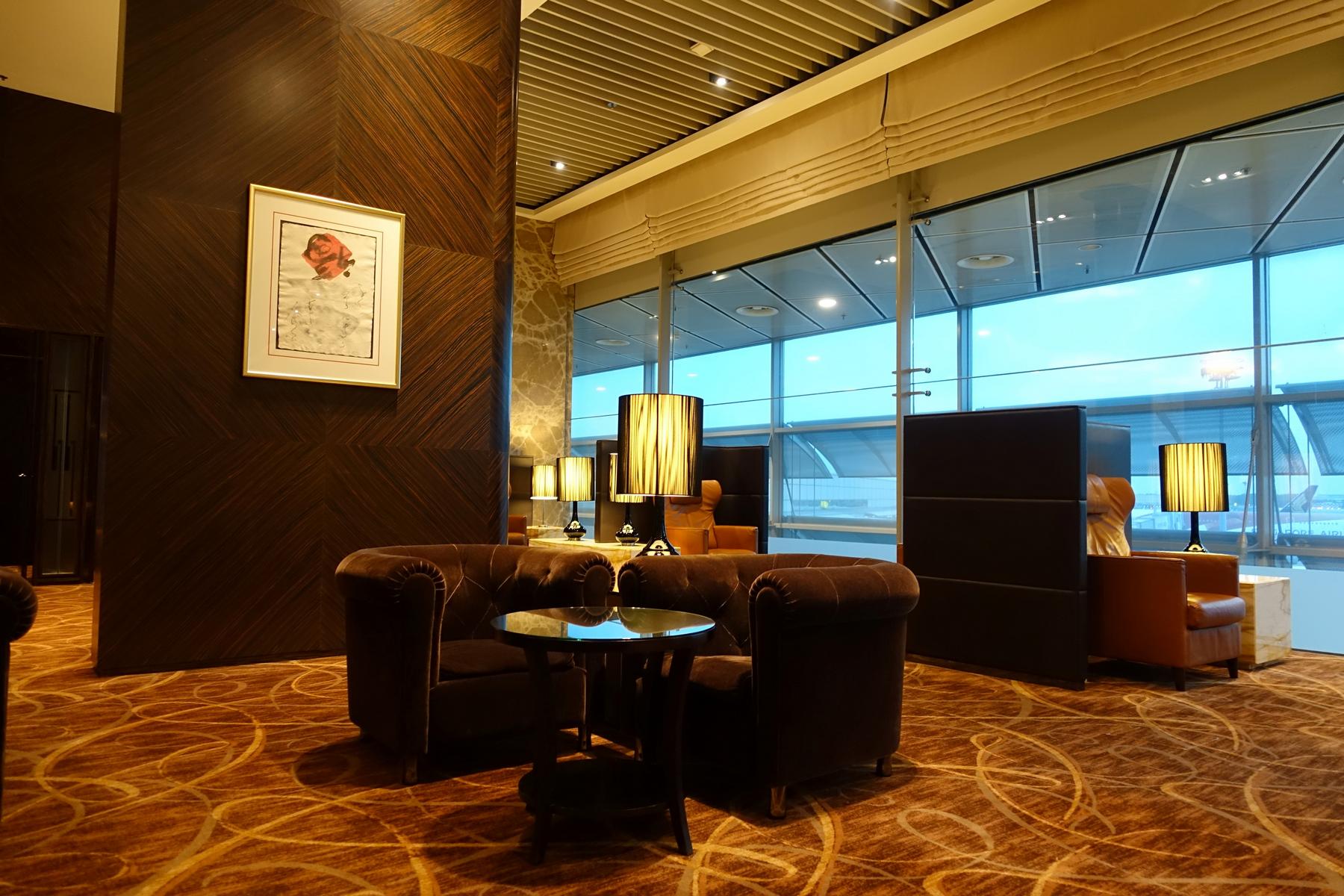 An opulent airport lounge with plush seating and floor-to-ceiling windows overlooking an airplane tarmac.