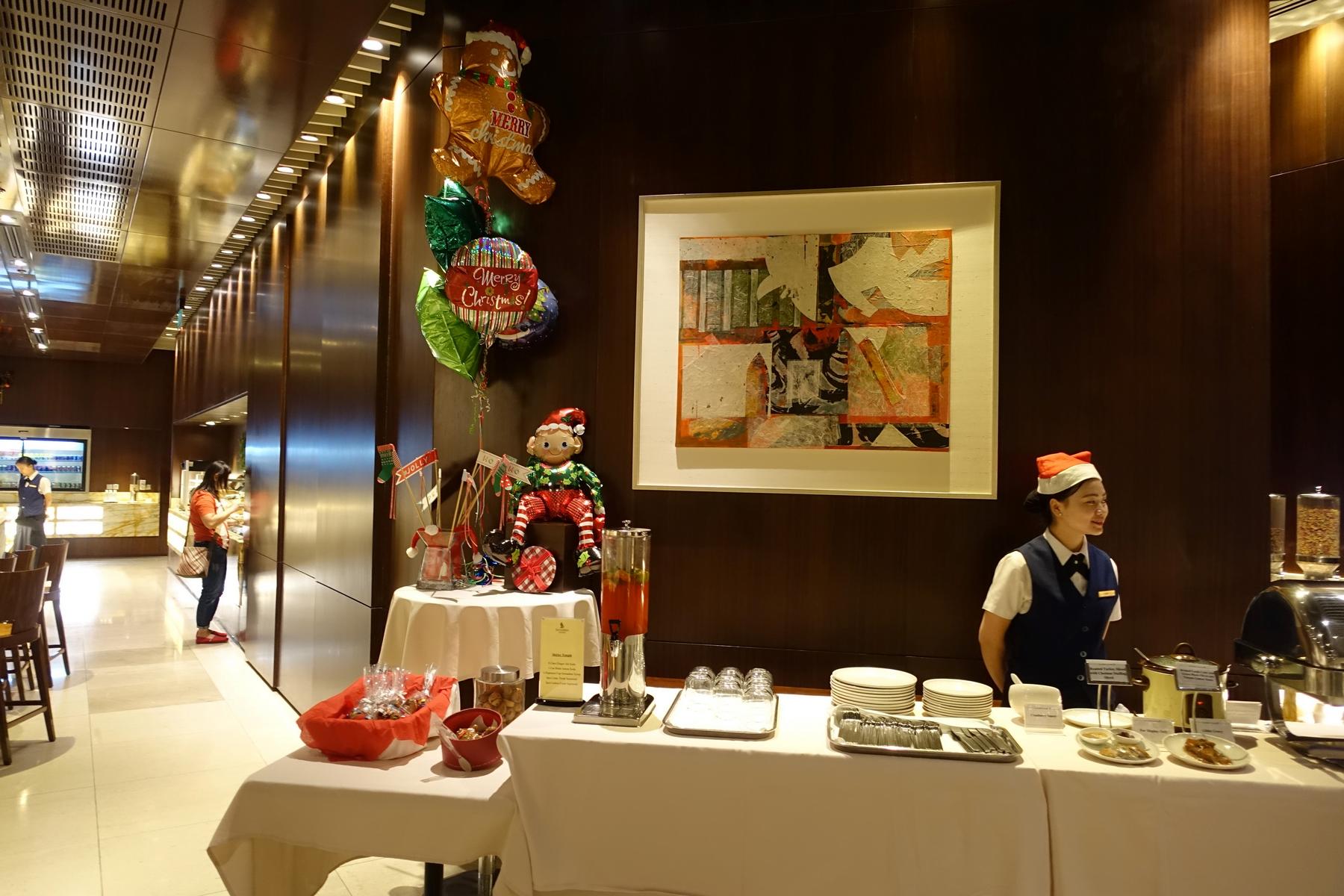 A Christmas-decorated buffet in a lounge with a staff member wearing a Santa hat.