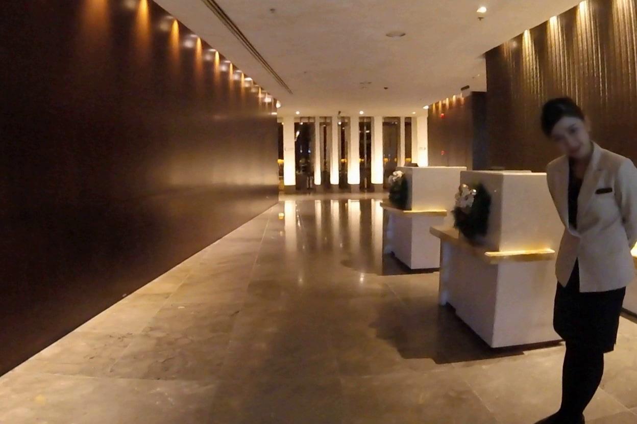 A smiling female attendant stands in a luxurious, warmly lit airport lounge.
