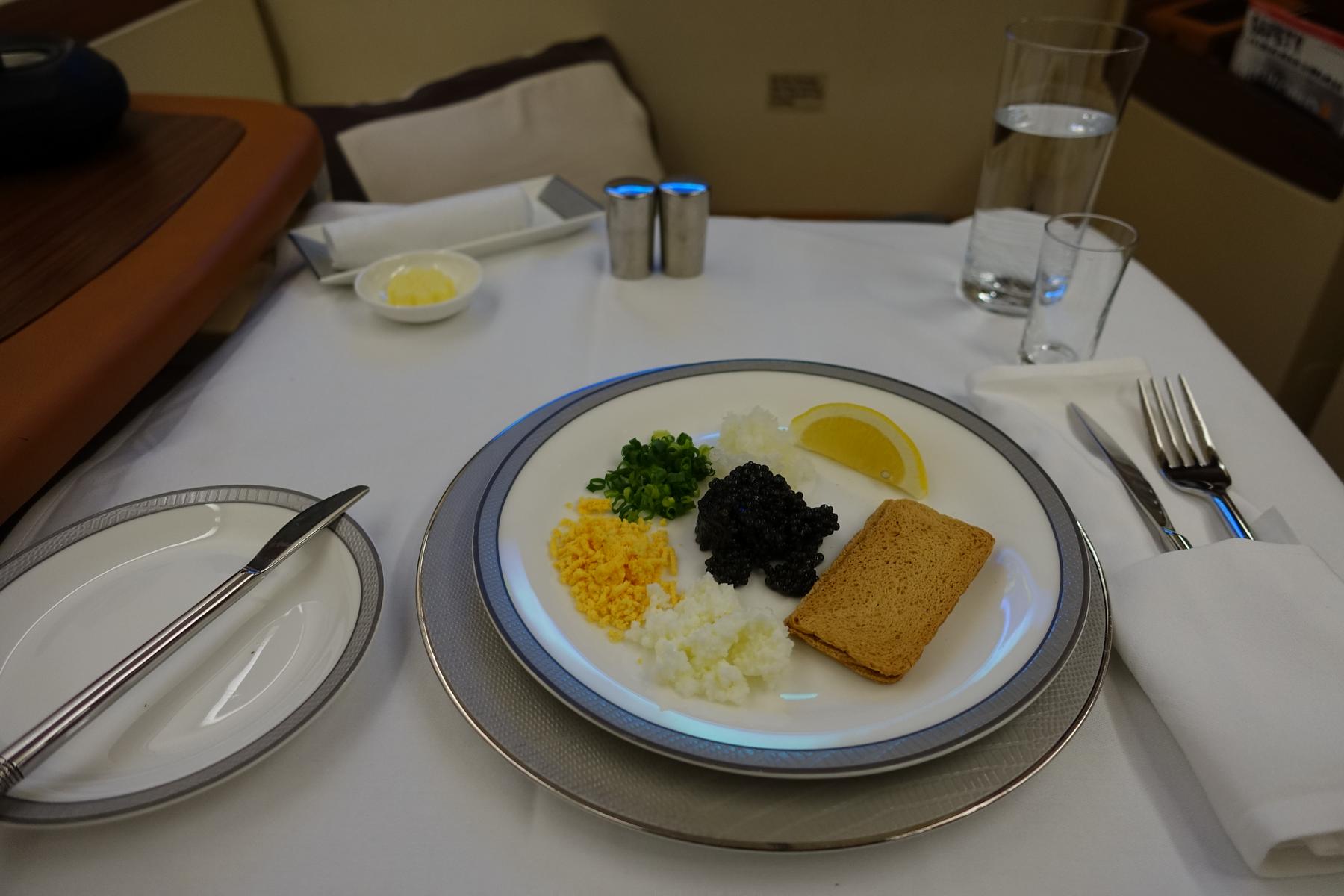 A plate of caviar with chopped egg, chives, and toast, served on a white tablecloth in Singapore Airlines Suites Class.