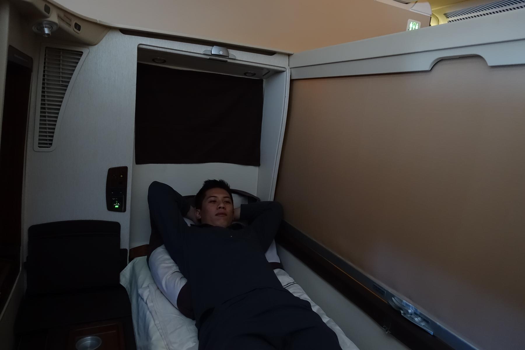 Man relaxing on a bed in a private first class airplane suite.