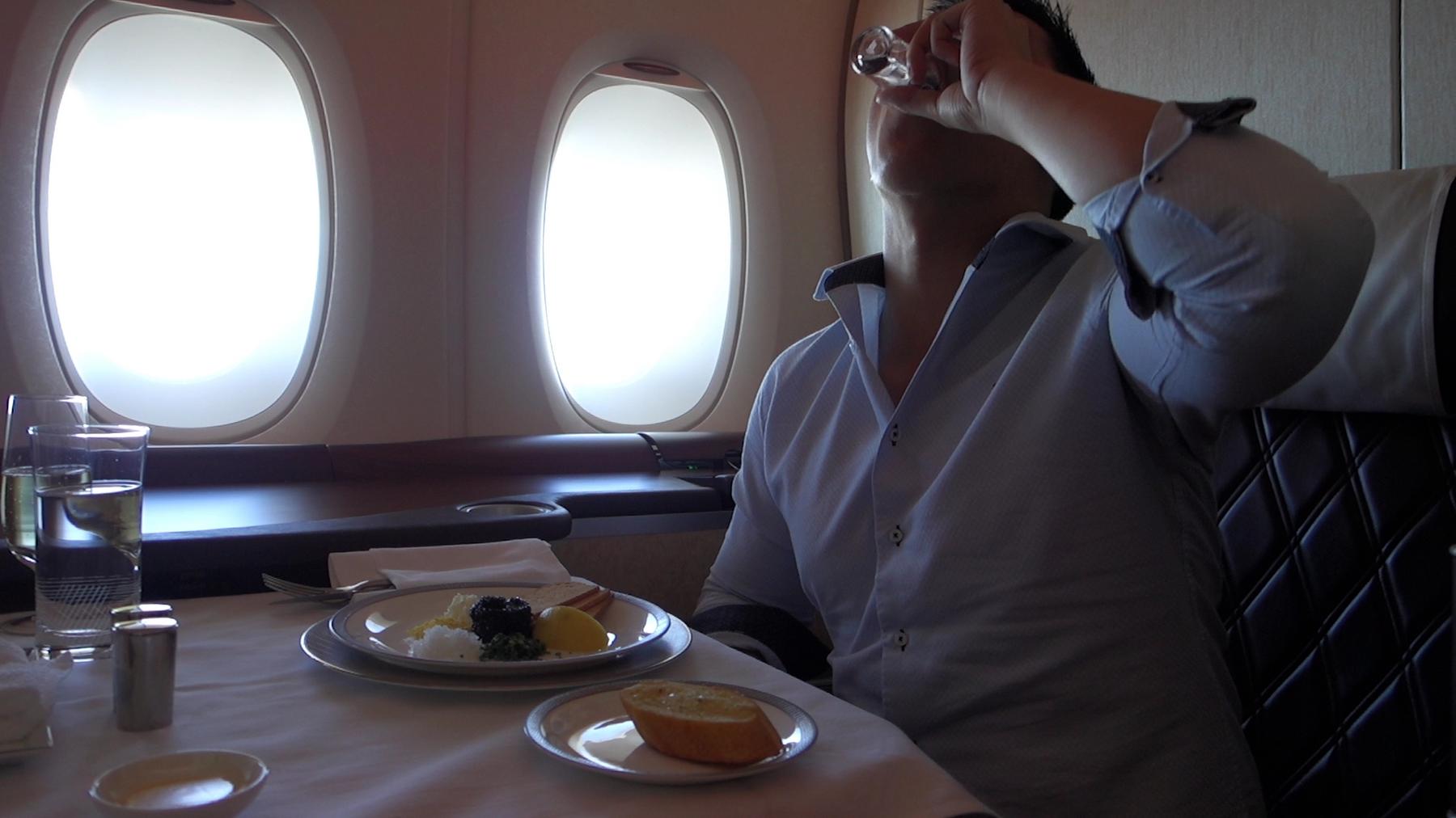 A passenger enjoys a drink and meal in a Singapore Airlines First Class Suite.