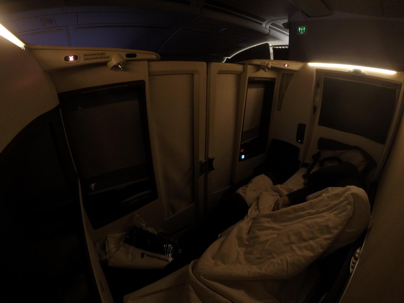 A person sleeps in a dim Singapore Airlines First Class Suite.