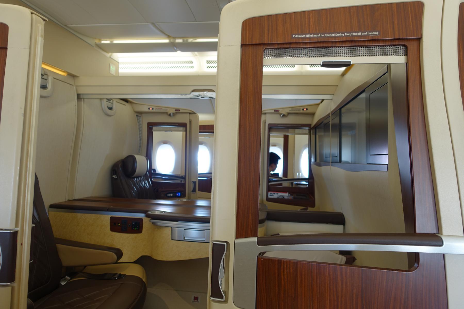 Two luxurious Singapore Airlines A380 First Class Suites with elegant wood and cream interiors.