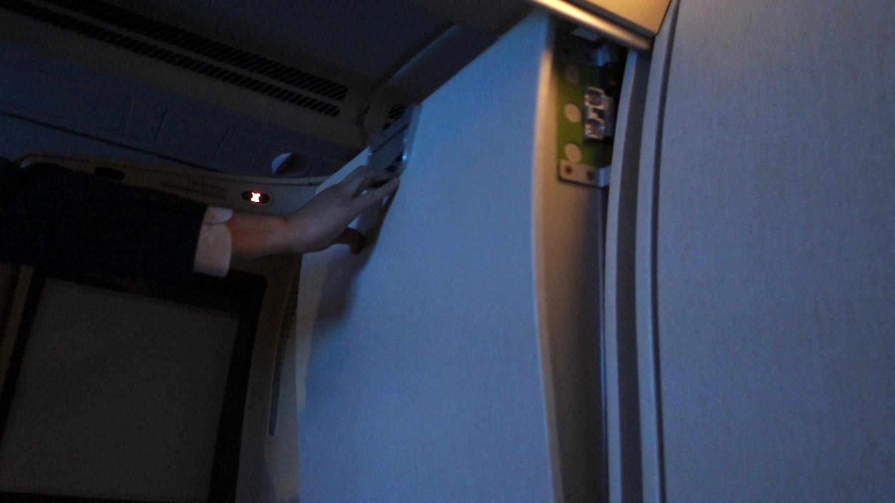 A hand closing the sliding privacy door of an airline suite.