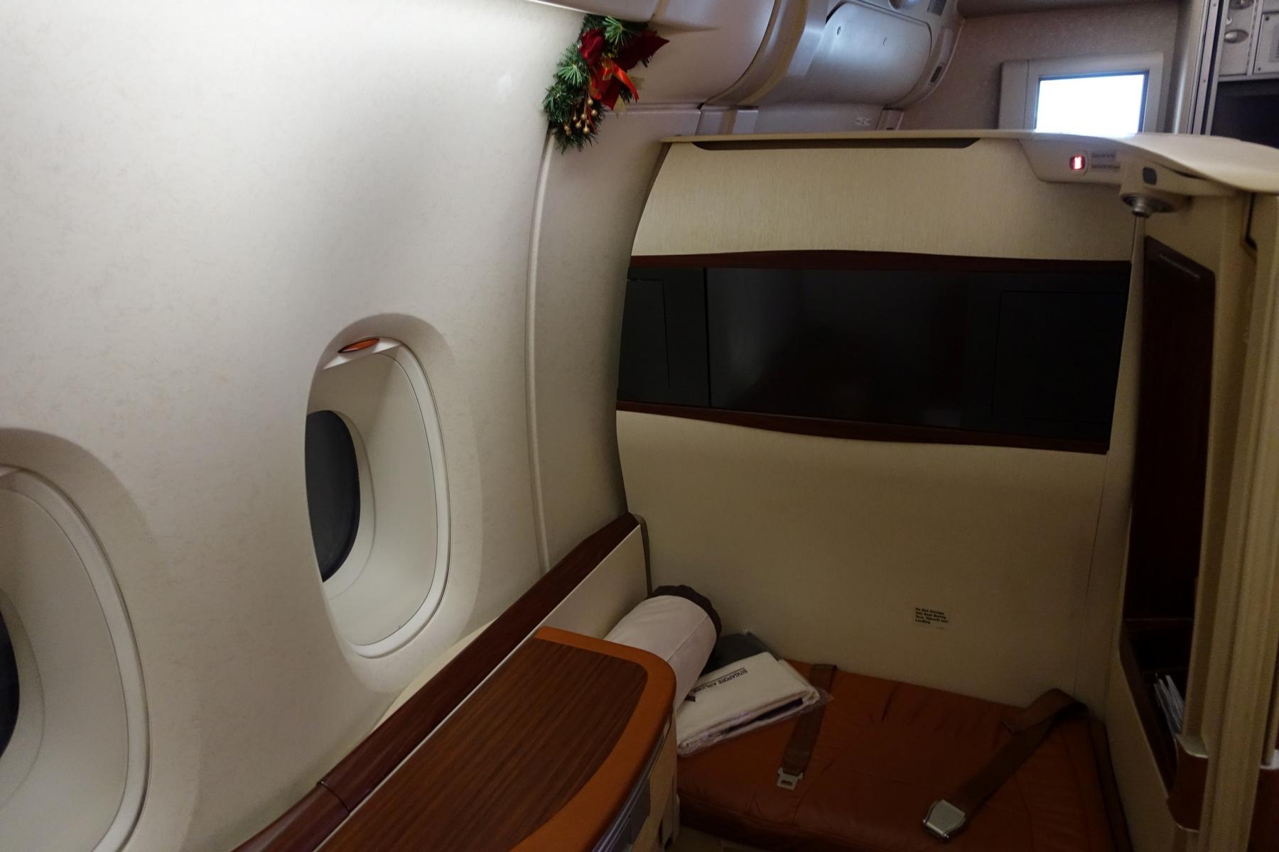 An opulent Singapore Airlines First Class Suite decorated for Christmas, showing a window and a large screen.