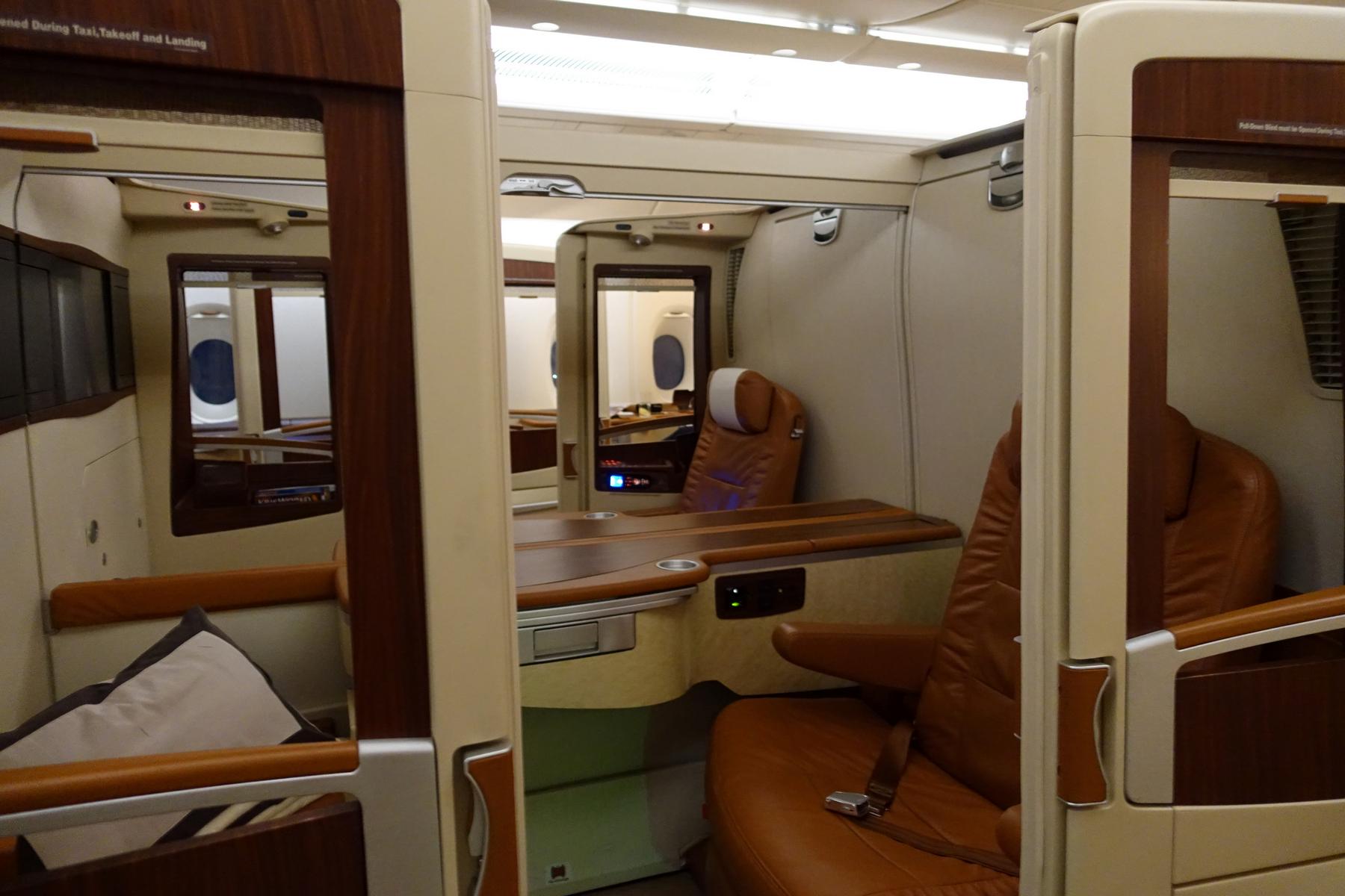 Luxurious Singapore Airlines First Class Suite interior with brown leather seats, wood accents, and a private feel.