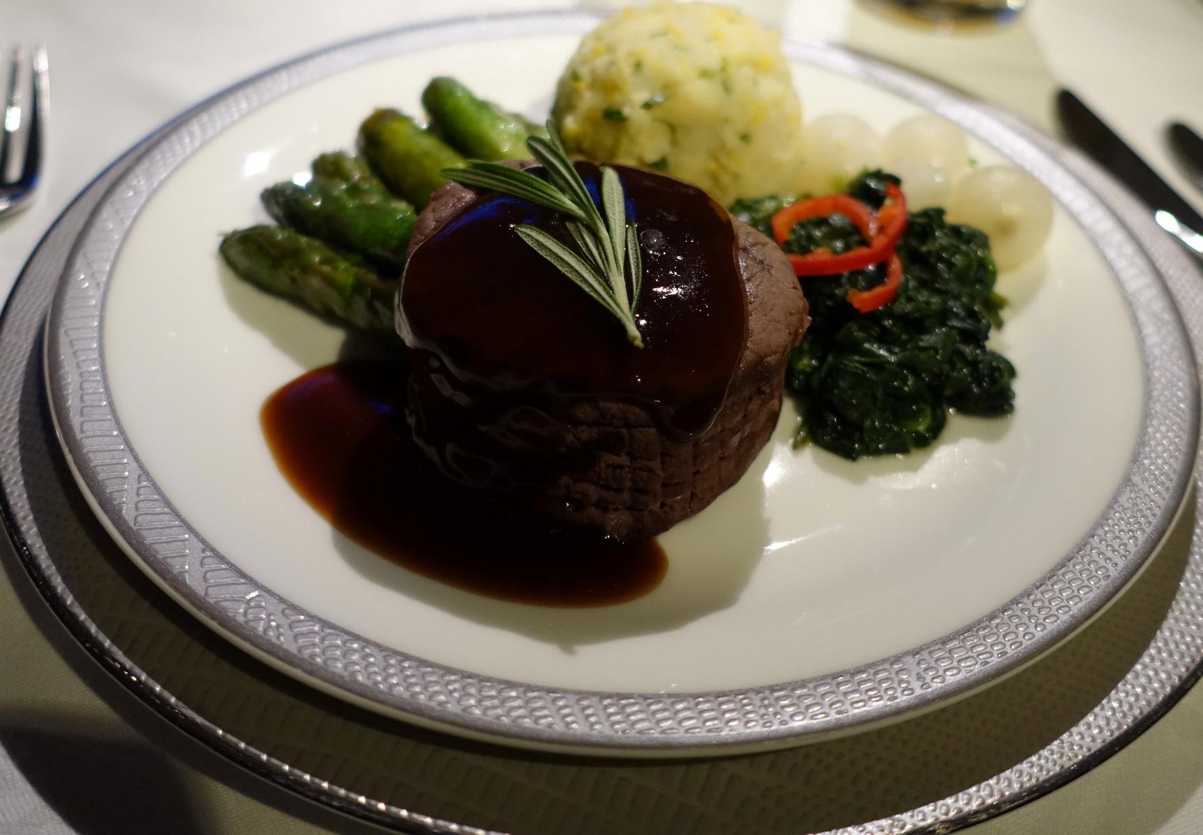 A perfectly plated steak with dark sauce and rosemary, asparagus, and mashed potatoes.