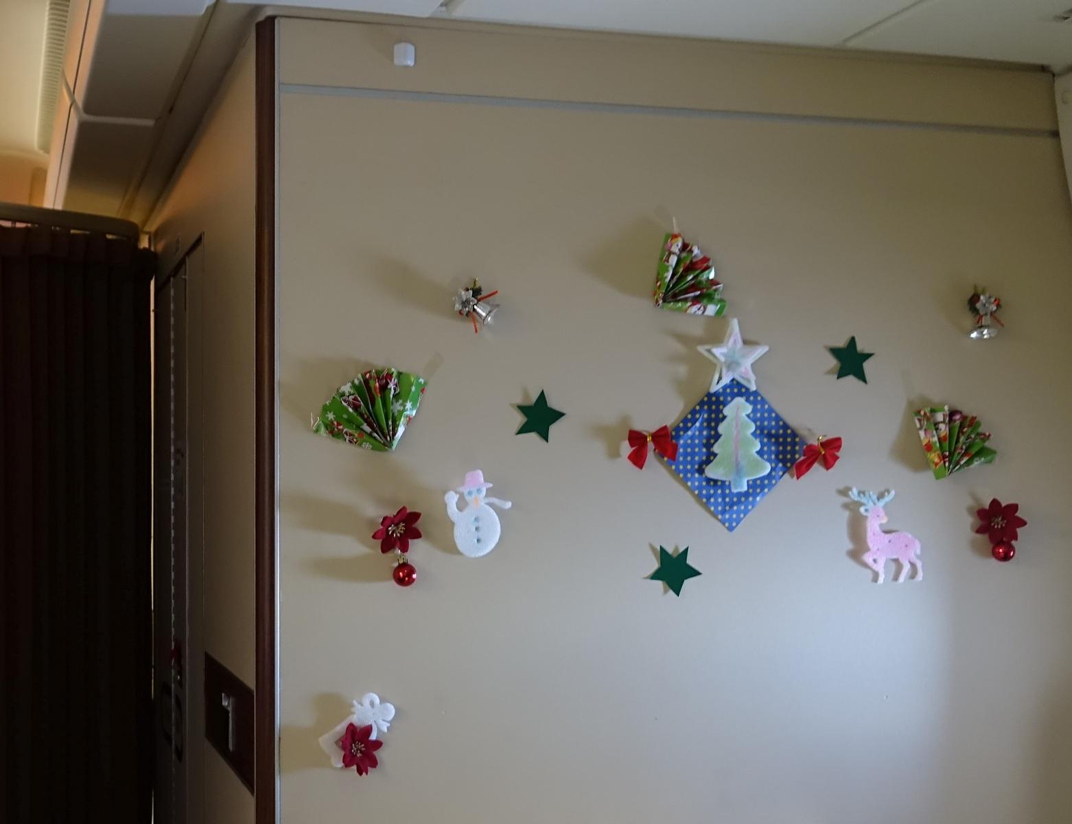 A light-colored wall decorated with assorted Christmas ornaments, including stars, a snowman, and a reindeer.