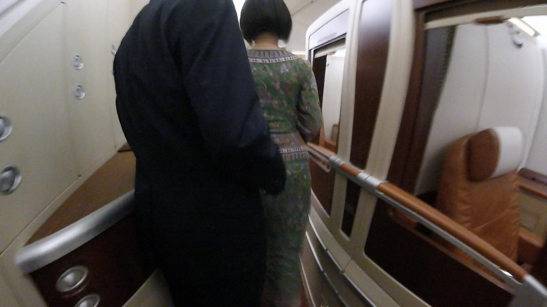 A passenger and a flight attendant walk down the luxurious aisle of a Singapore Airlines First Class Suite.