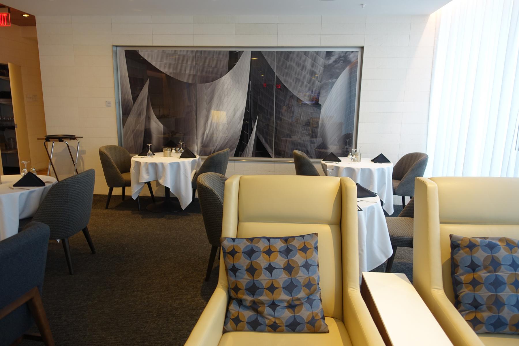 The dining area of the Star Alliance lounge features set tables, comfortable seating, and a large modern art installation.