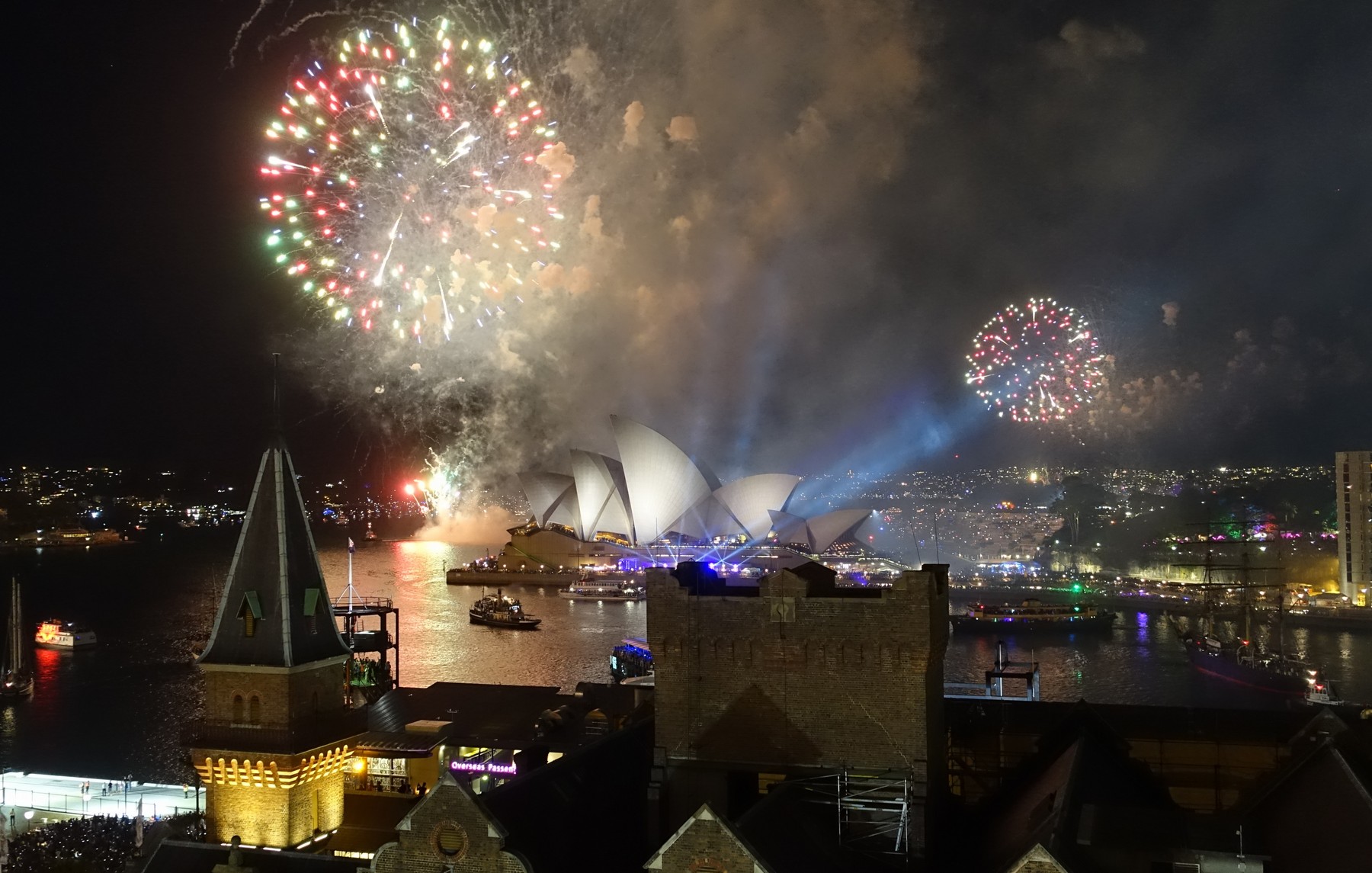 New Year's Eve fireworks explode above the Sydney Opera House and Harbour at night.