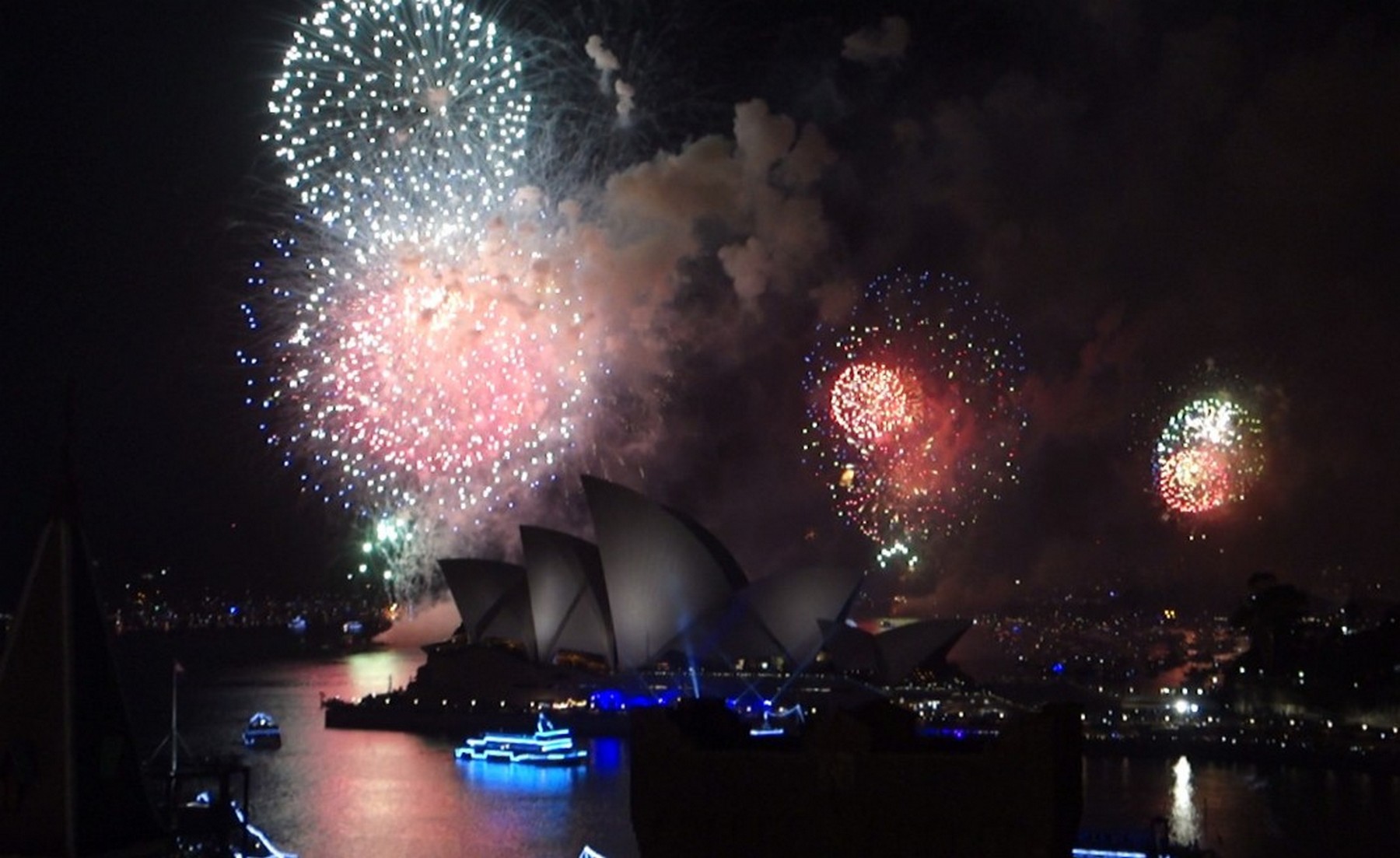New Year's Eve fireworks explode over the Sydney Opera House at night.