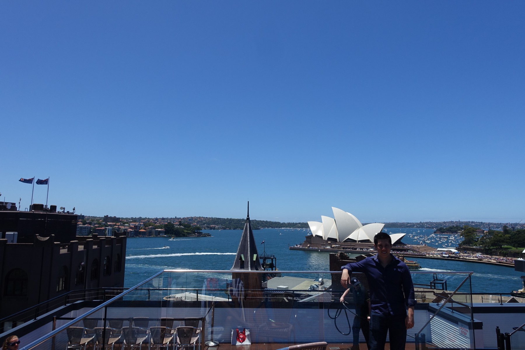 A man on a rooftop terrace overlooking Sydney Harbour and the iconic Opera House from the Old Holiday Inn.