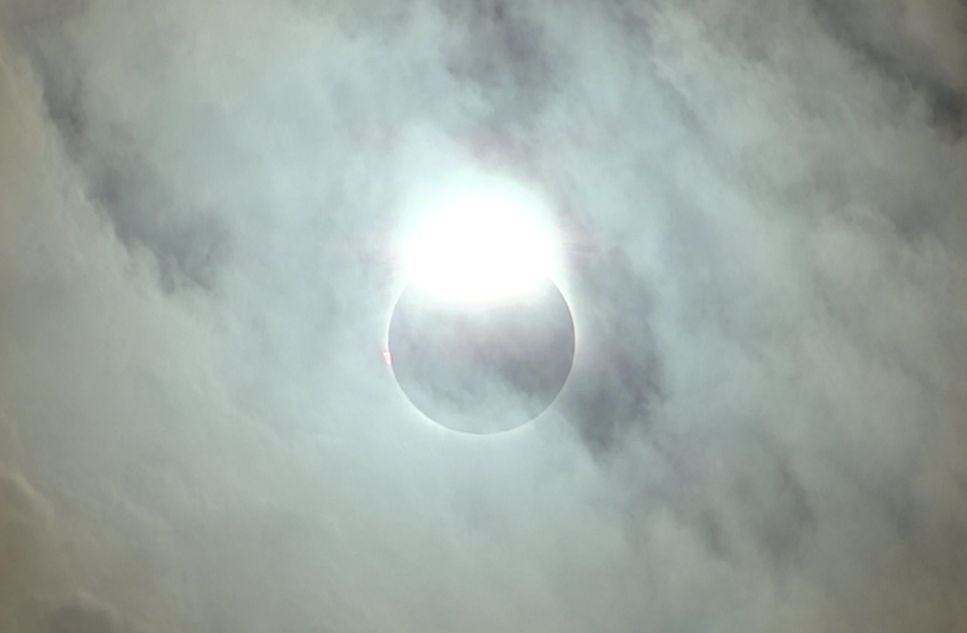 The sun's bright "diamond ring" effect shines through hazy clouds during a total solar eclipse.