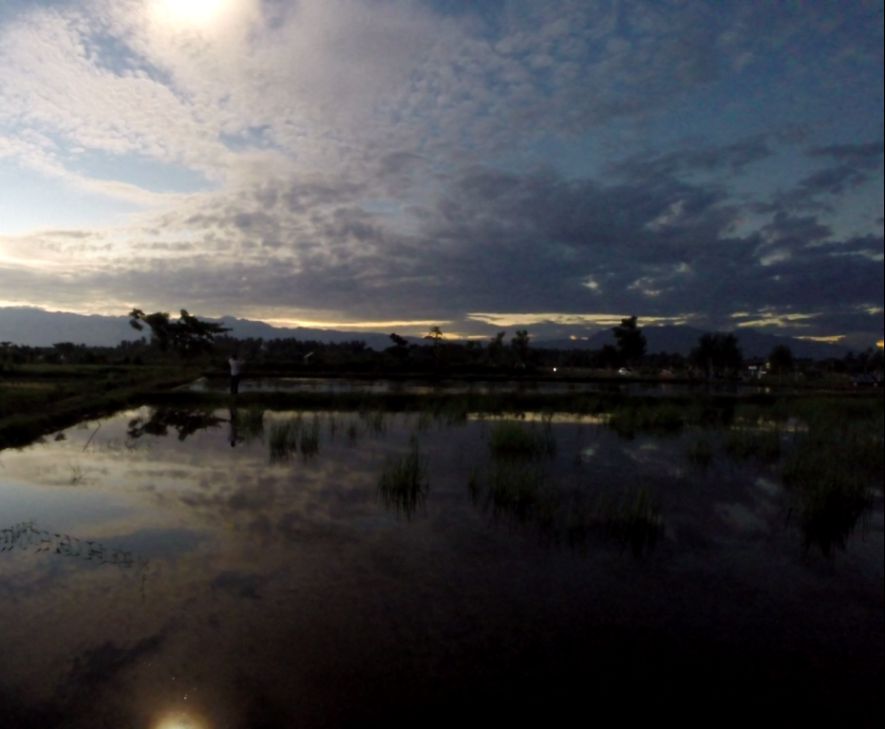 A dramatic sky with dark and bright clouds reflecting in still water during a total solar eclipse.