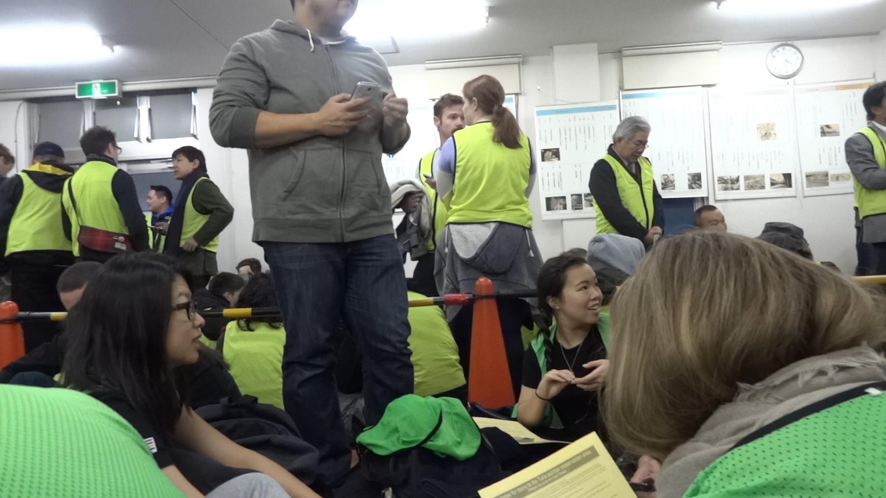 A group of early-morning visitors wearing bright vests wait indoors for the Tsukiji tuna auction.