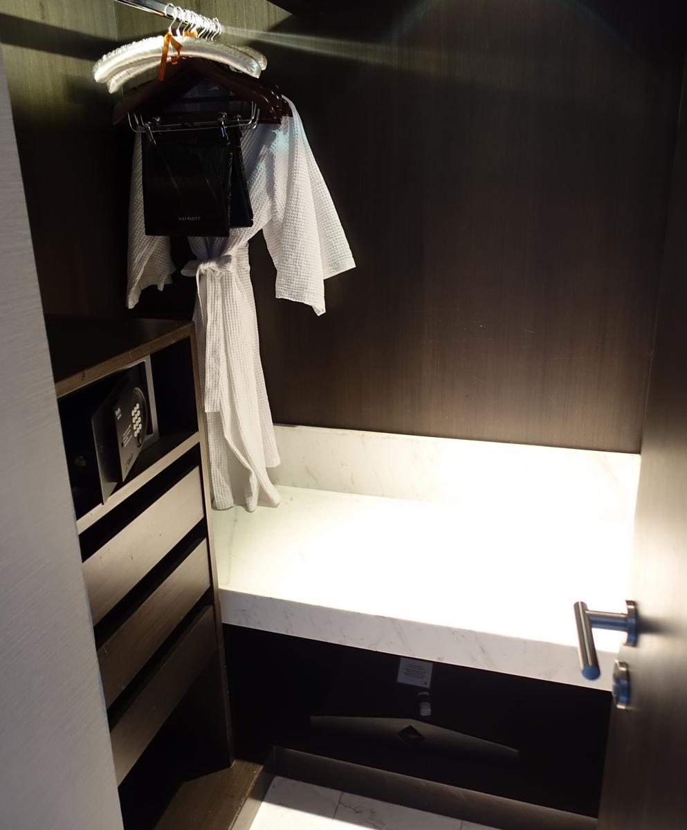 Hotel closet with a white bathrobe, safe, and marble countertop.