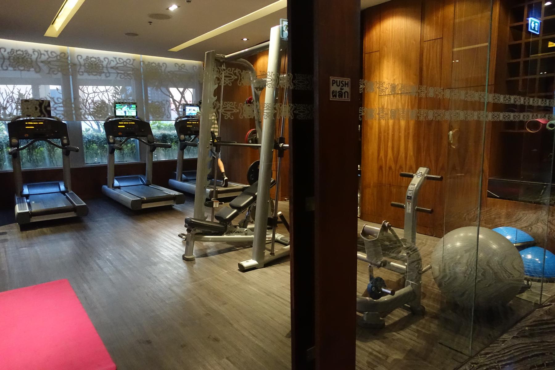 A modern hotel gym with treadmills, weight machines, and exercise balls.