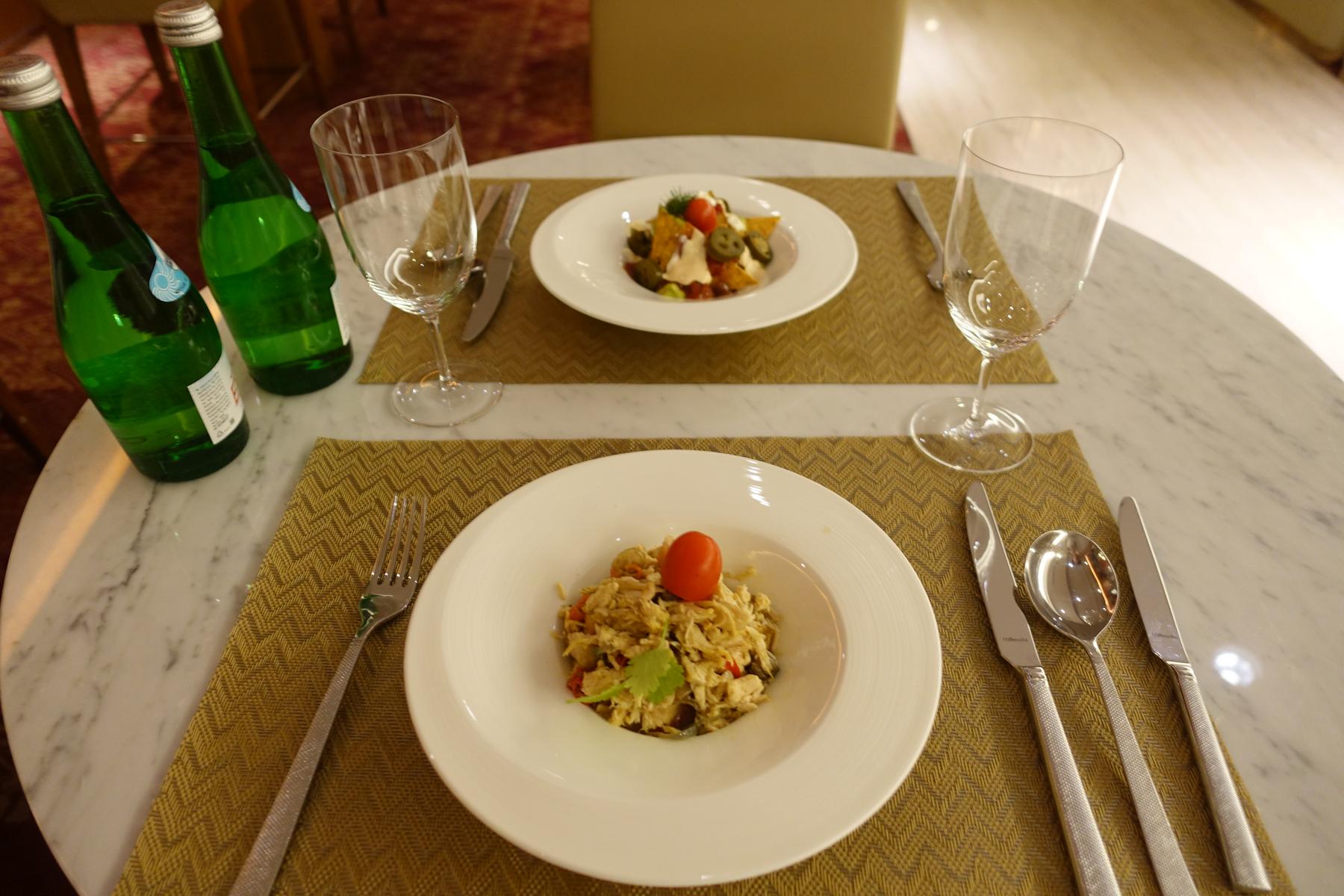 An elegant table set for two with gourmet dishes, wine glasses, and bottled water.