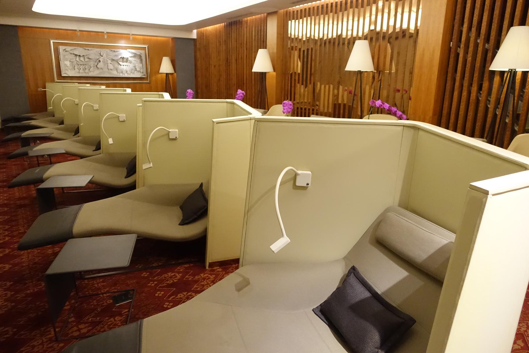 A lounge area features rows of semi-private reclining daybeds with side tables.