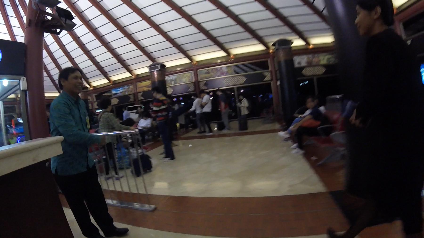 A bustling airport terminal with a unique sloped, paneled ceiling.