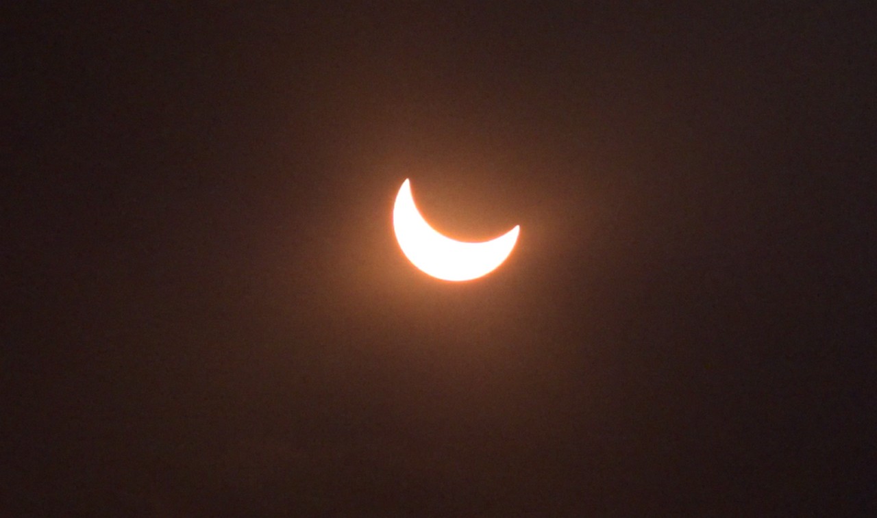 A partial solar eclipse shows the sun as a bright crescent against a dark sky.