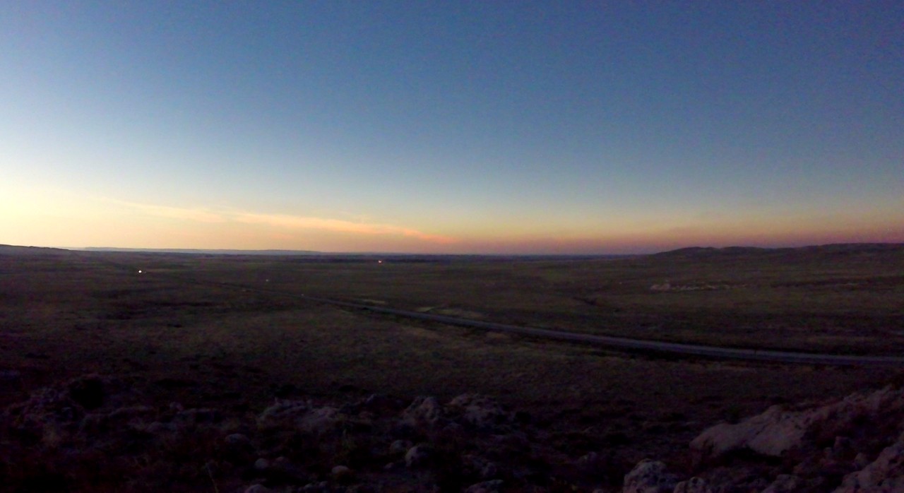 Vast, dark Nebraska plains with a road under a twilight sky.