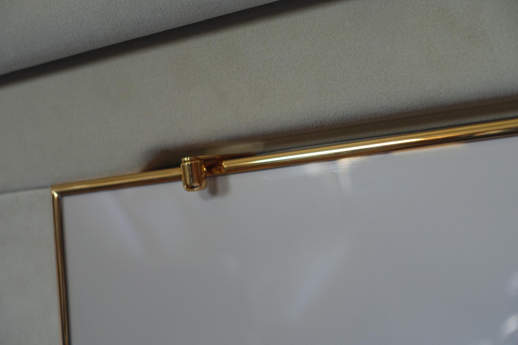 Close-up of a shiny gold trim detail against a light gray panel in a private jet interior.