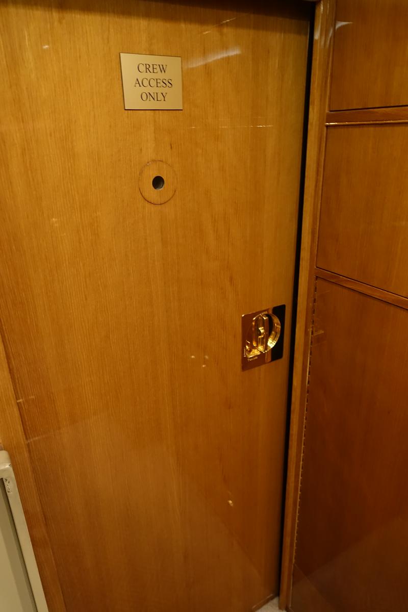 A polished wooden door with a "CREW ACCESS ONLY" sign and a gold handle.