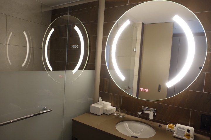 Modern hotel bathroom with an illuminated mirror and a digital clock displaying 88:88.