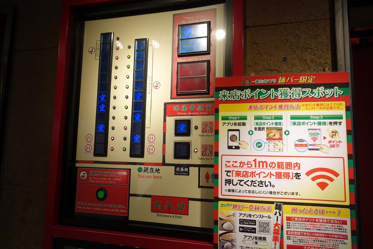 A digital display in a Japanese restaurant shows available seats with glowing blue squares and instructions for a loyalty program.
