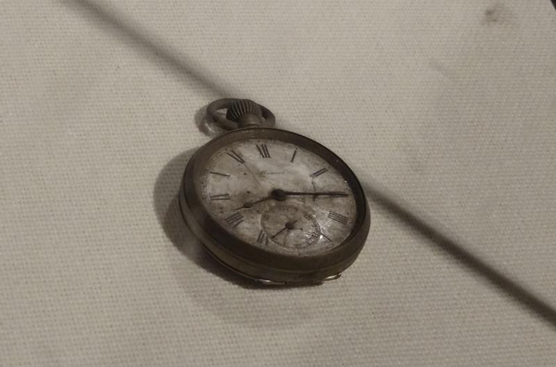 A damaged pocket watch with its hands frozen at 8:15.