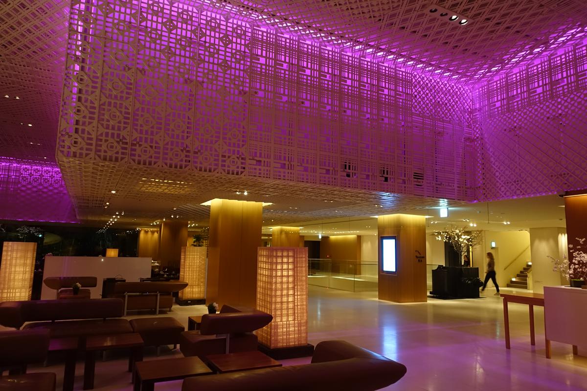 The modern lobby of the Hyatt Regency Kyoto featuring purple ceiling lights and decorative screens.