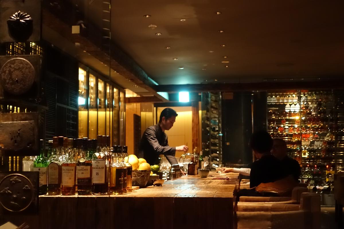 A bartender prepares drinks behind a wooden bar at the Hyatt Regency Kyoto.