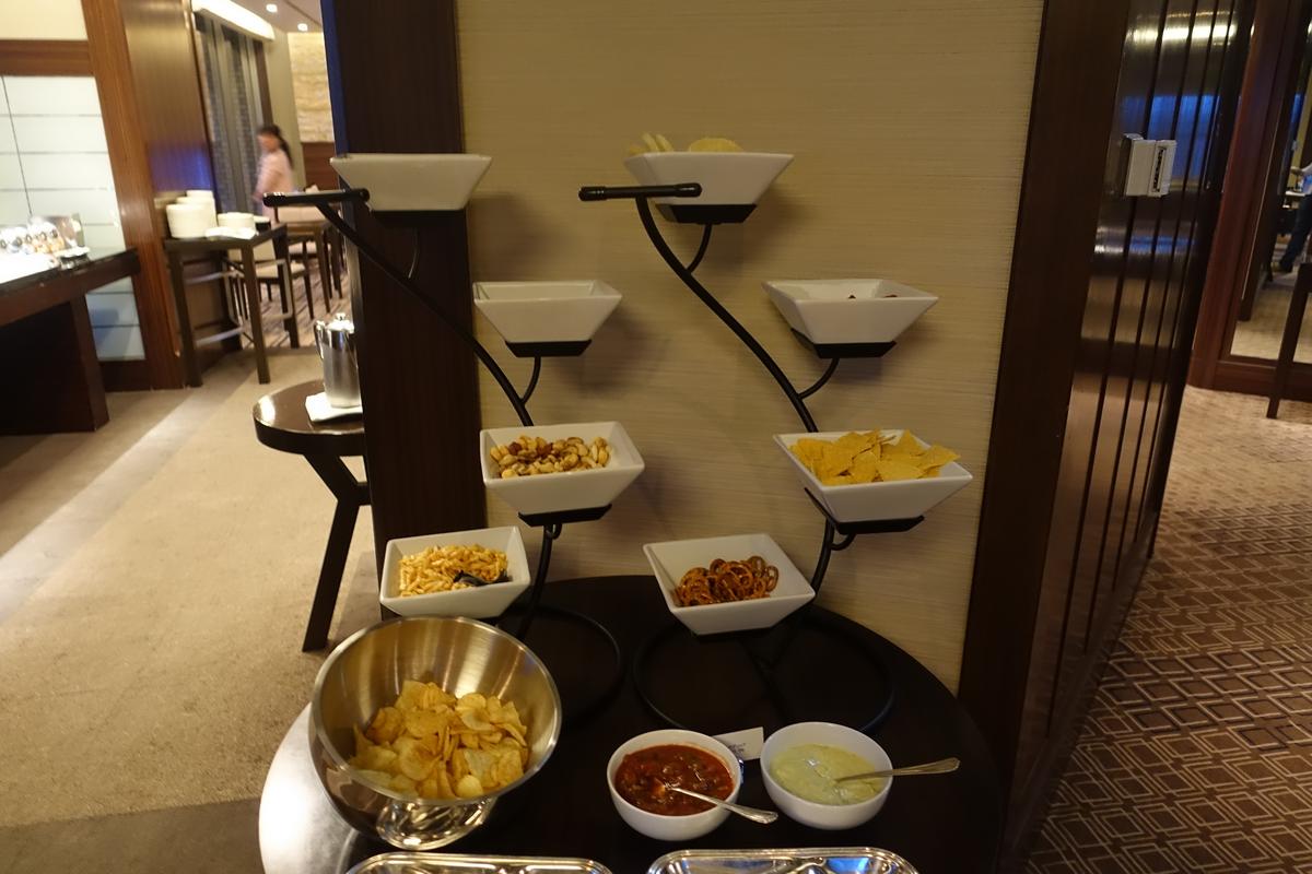 A multi-tiered snack display featuring various chips, nuts, and dips.