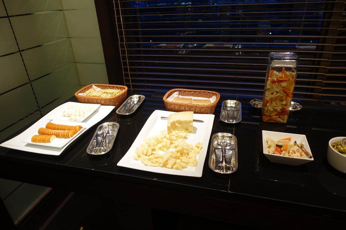 A buffet display featuring cheese, crackers, and pickled vegetables.