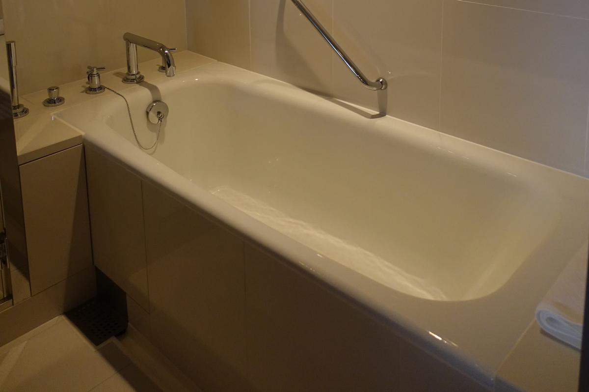 A white bathtub with chrome faucet, drain, and a grab bar.