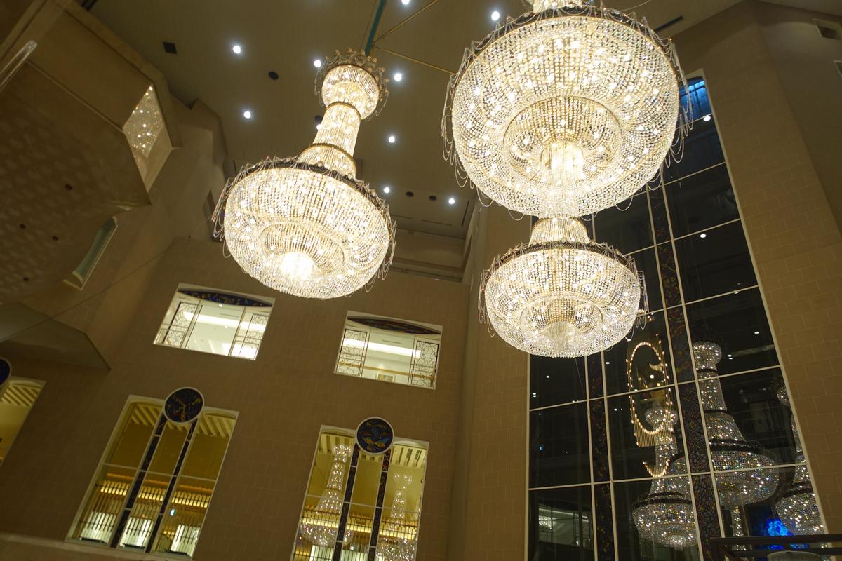 Ornate crystal chandeliers illuminate a grand hotel atrium.