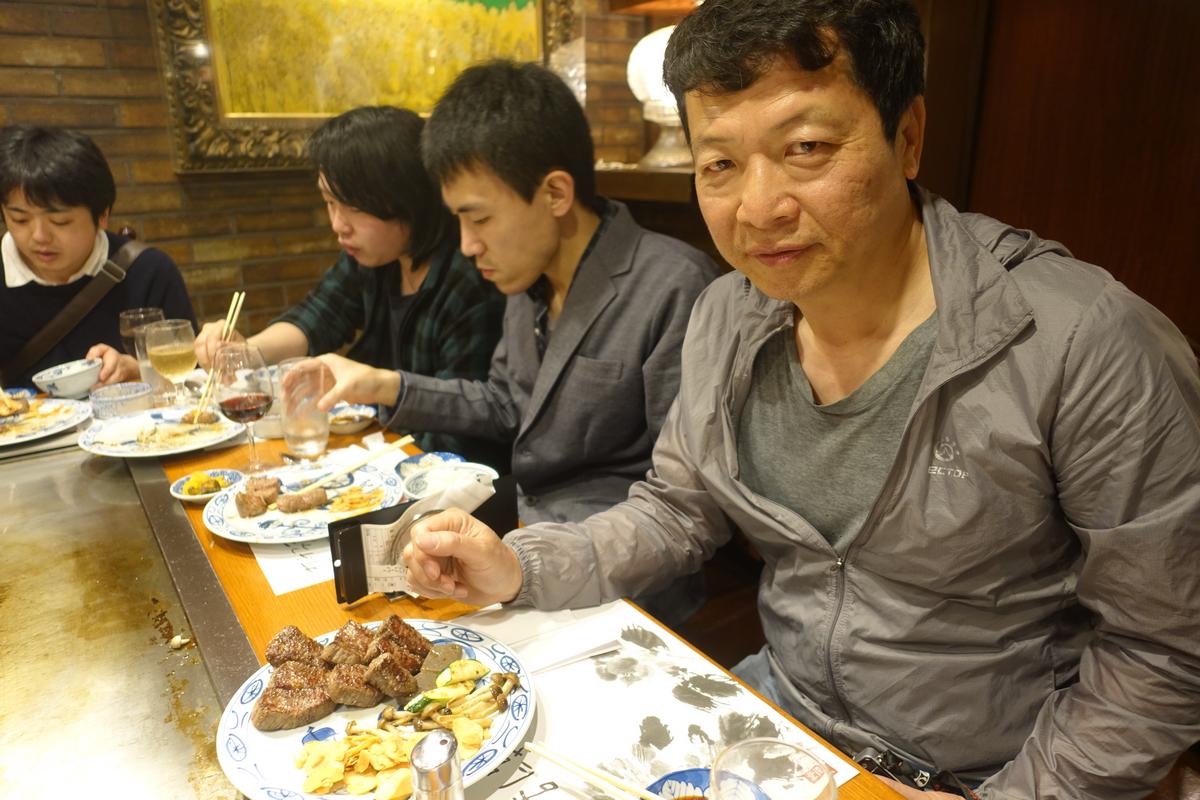A group of people dining at a restaurant with plates of Kobe beef and wine.