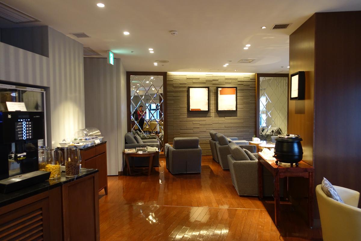 A modern hotel lounge with comfortable seating and a self-serve coffee station.