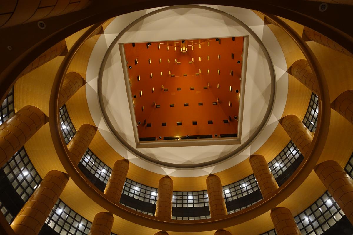 An upward view of the Hyatt Regency Fukuoka's circular atrium with golden walls and a square ceiling.