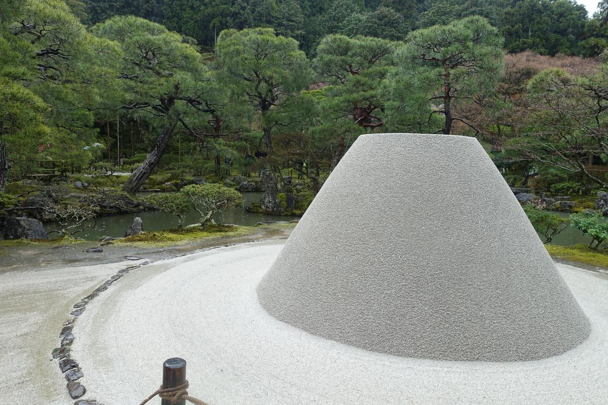A large, cone-shaped mound of raked sand in a Kyoto Zen garden.