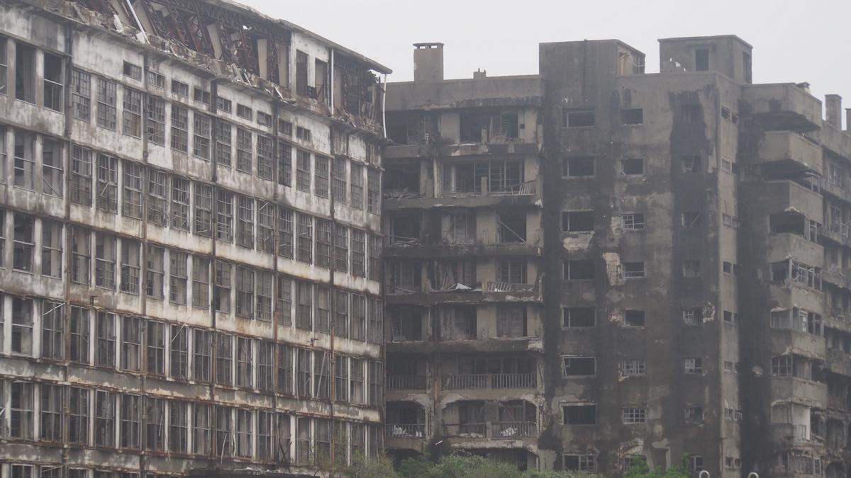 Two large, dilapidated concrete buildings with many broken windows on Hashima Island.